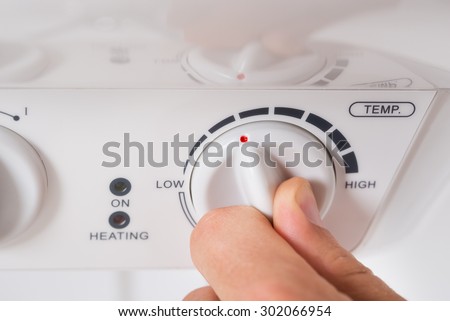 Close-up Of Person Hands Turning The Knob Of Electric Boiler