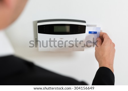 Close-up Of Businessperson Hands Inserting Keycard In Security System To Unlock Door