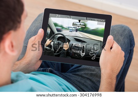 Young Man Playing Car Racing Game On Digital Tablet At Home