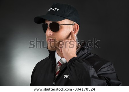 Secret Service Agent Listening To Earpiece Over Black Background