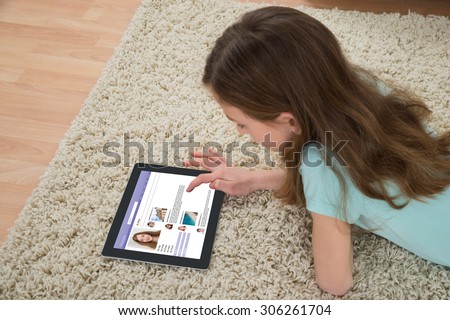 Girl Using Social Networking Site On Digital Tablet At Home