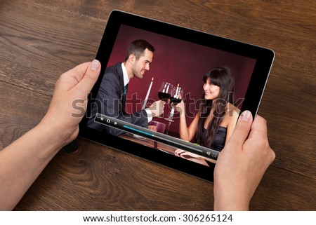 Close-up Of Person Hands With Digital Tablet Showing Video At Desk