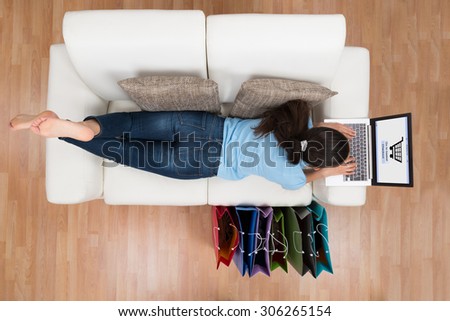 High Angle View Of Young Happy Woman On Sofa Shopping Online With Laptop