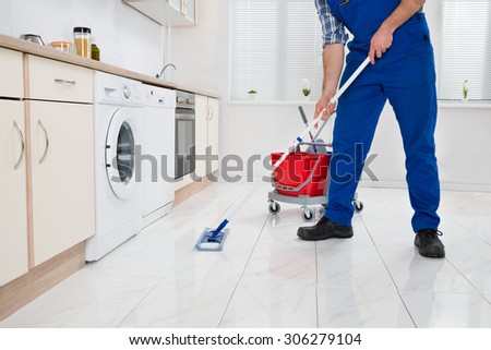 Close-up Of Worker Cleaning Floor With Mop In Kitchen Room Close-up Of Worker Cleaning Floor With Mop In Kitchen Room