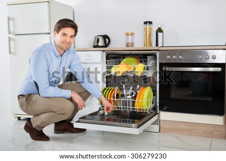 Young Happy Man Putting Dishwasher Soap Tablet In Detergent Dishwasher Box In Kitchen Room