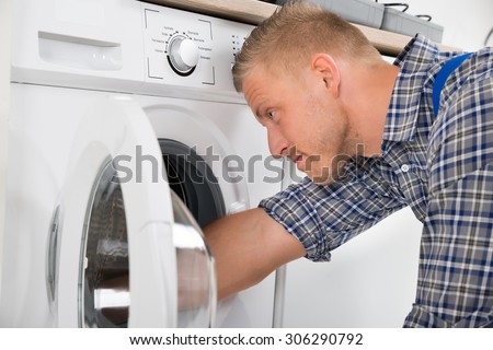 Close-up Of Professional Handyman In Overall Repairing Washing Machine