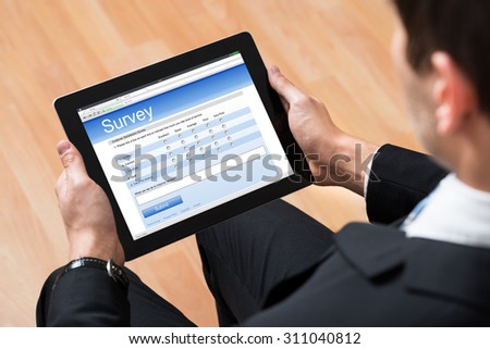 Close-up Of Businessman Looking At Blank Online Survey Form On Digital Tablet