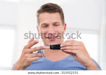 Close-up Of Young Happy Man Checking Blood Sugar Level With Glucometer