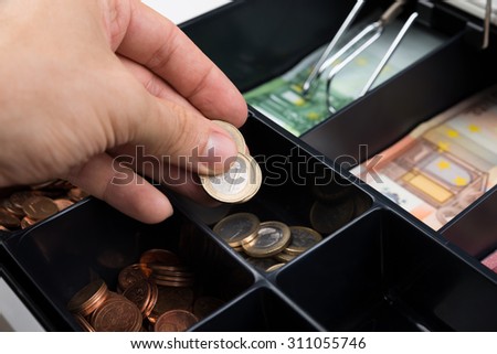 Close-up Of Person Hands Putting Coins In Cash Register