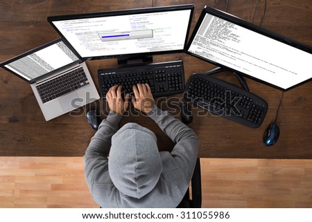 High Angle View Of Hacker Stealing Information From Computers At Desk