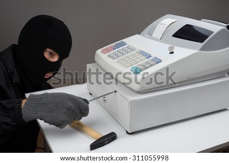 Close-up Of Thief Opening Cash Register Drawer With Screwdriver