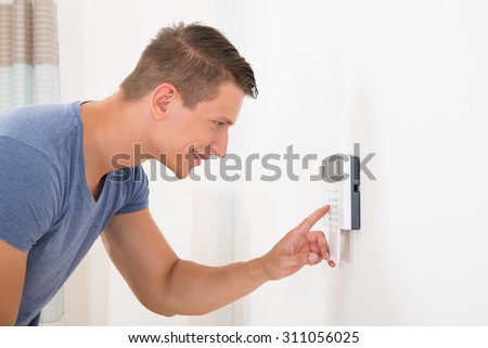 Young Happy Man Entering Code In Door Security System