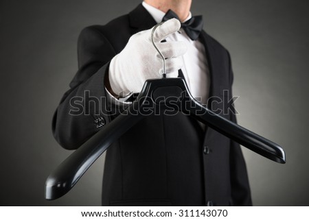 Close-up Of Housekeeper In Suit Holding Black Plastic Hanger