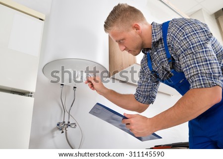 Male Worker With Clipboard Adjusting Temperature Of Water Heater