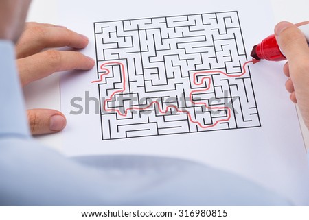 Close-up Of Person With Red Marker Pen Solving Maze Puzzle
