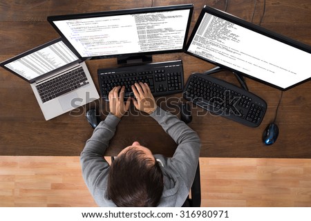 Young Man Stealing Data From Computers And Laptop At Desk