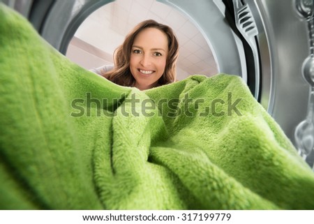 Happy Woman Putting Green Towel View From Inside The Washing Machine Appliance