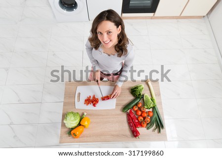 High Angle View Of Woman Cutting Vegetable On Chopping Board In Kitchen