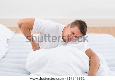 Young Man On Bed Suffering From Backache