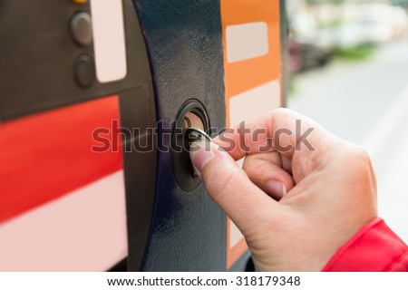Close-up Of Person Hands Inserting Coin Into Parking Meter