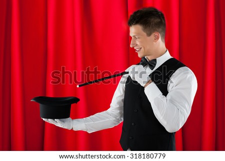 Young Happy Magician With Magic Wand And Black Hat