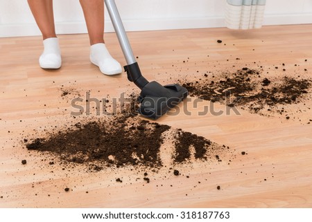 Close-up Of Person With Vacuum Cleaner Cleaning Dirt On Floor