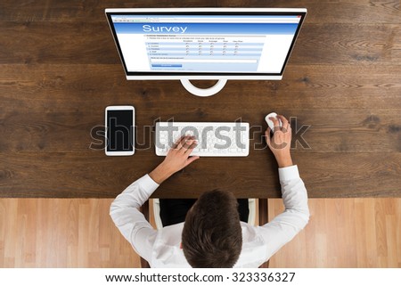 High Angle Of Young Businessman Filling Online Survey Form On Computer
