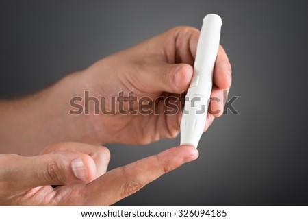 Close-up Of Person Hands Checking Blood Sugar Level With Glucometer