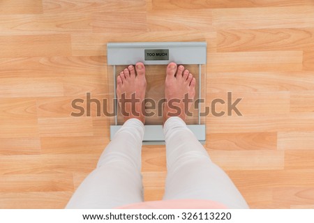Low Section Of Woman Standing On Weighing Scale
