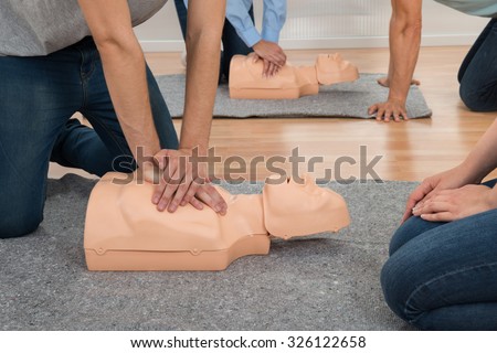 Students Practicing Cpr Chest Compression On Dummy In Class