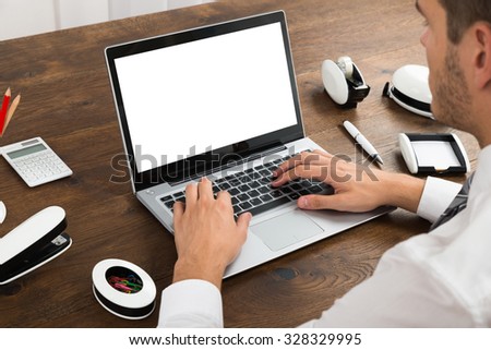 Close-up Of Businessperson Working On Blank Display Laptop At Desk