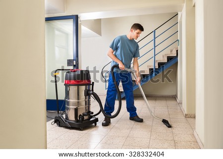 Happy Male Worker Cleaning Floor With Vacuum Cleaner Appliance