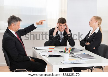 Mature Businessman Arguing With His Two Co-workers In Office