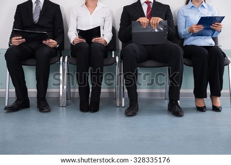 Close-up Of Businesspeople With Files Sitting On Chair
