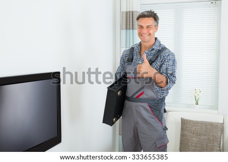 Portrait of happy male technician with TV set top box at home