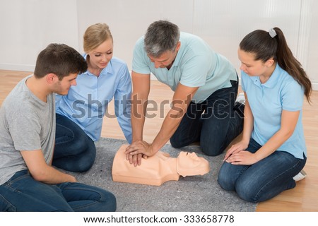 Mature Male Instructor Showing Cpr Training On Dummy To His Student