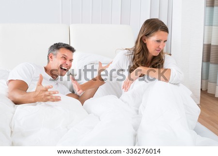 Portrait Of Unhappy Couple Disputing On Bed