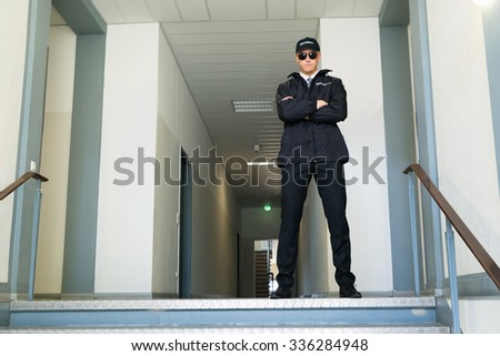 Male Security Guard Standing With Folded Arms At The Entrance