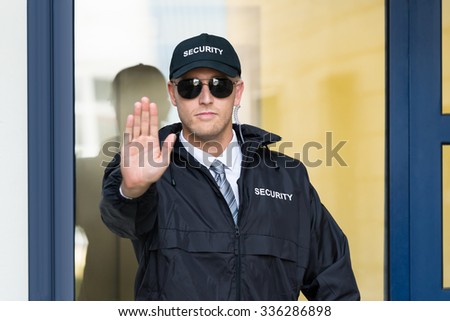 Close-up Of A Male Security Guard Making Stop Sign With Hand Wearing Sunglasses