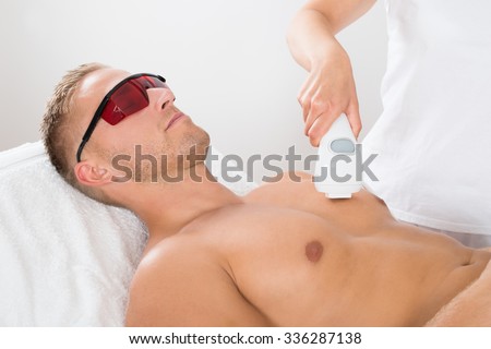 Female Beautician Giving Laser Epilation On Man\'s Chest