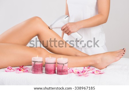 Low section of young woman getting laser treatment on leg at spa
