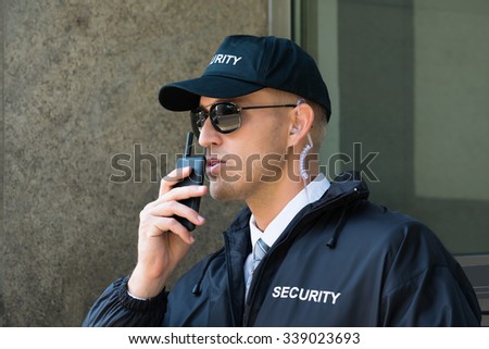 Portrait Of Young Security Guard Using Walkie-talkie Radio