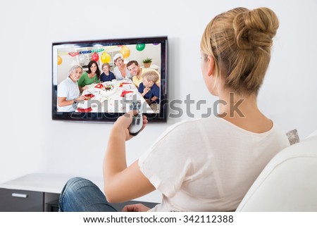 Young woman watching television while sitting on sofa in living room