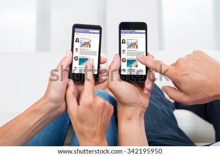 Close-up Of Two People Hands Chatting On Social Networking Site On Mobile Phones