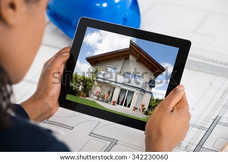 Close-up Of A Woman Holding Digital Tablet Over Blueprint