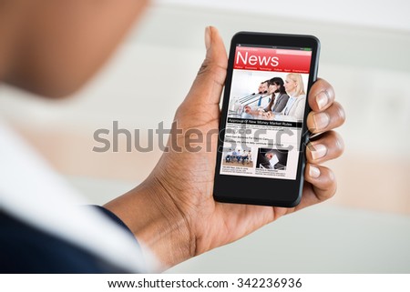 Close-up Of A Woman\'s Hand Reading News On Mobile Phone