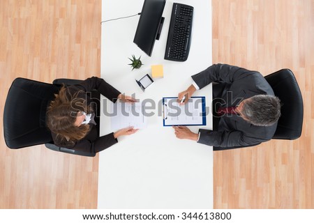 High Angle View Of Mature Businessman Interviewing Female Candidate For Job