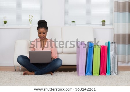 Young African Woman Sitting On Carpet Shopping Online