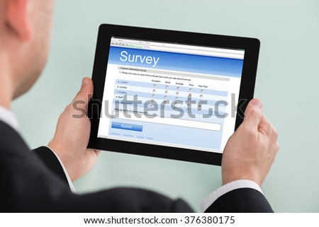 Close-up Of Businessman Looking At Online Survey Form On Digital Tablet