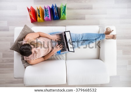 Young Woman Sitting On Sofa With Laptop Shopping Online